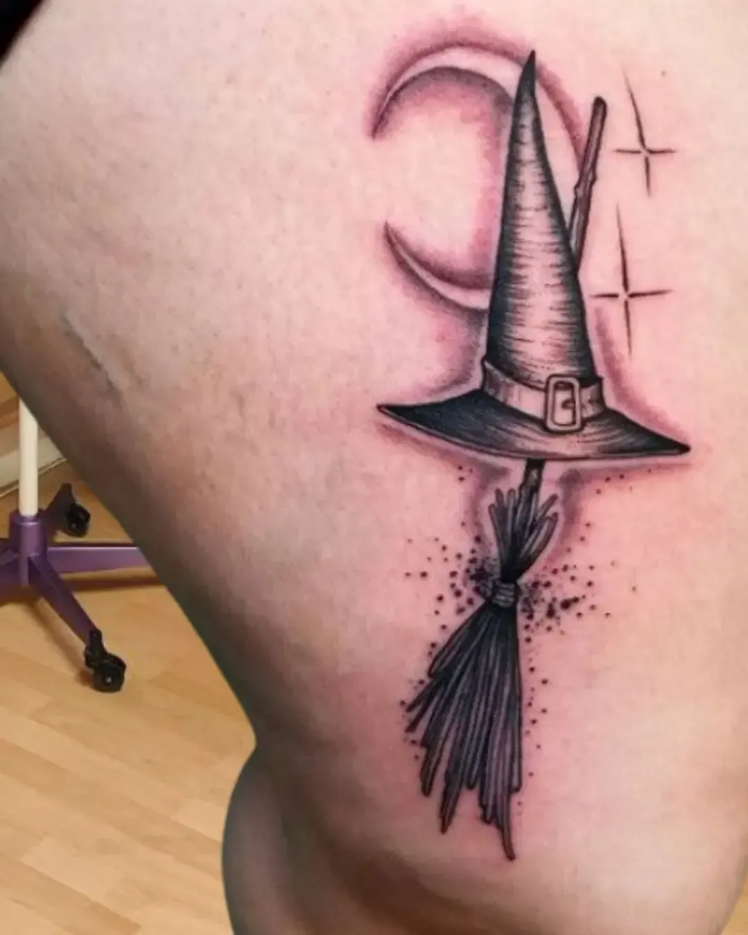 Tatouage sorcière minimaliste avec chapeau, balai, lune et étoiles – symbole de magie, mystère et féminité, réalisé par Magic Ink à Fribourg.