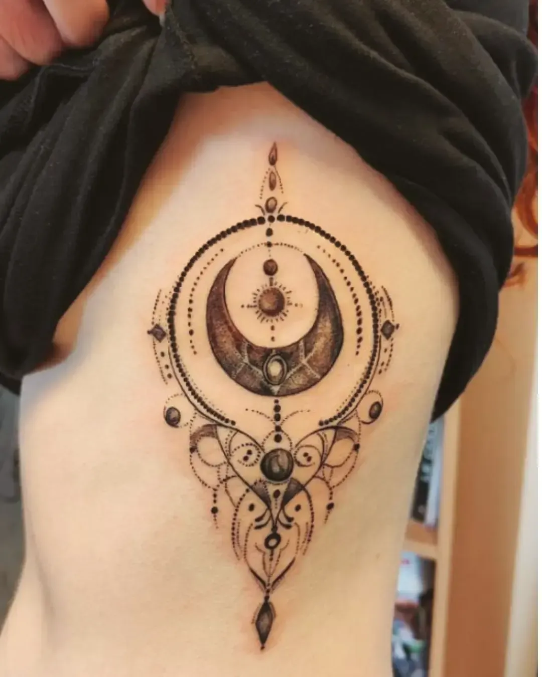 Tatouage ornemental de lune et symboles cosmiques en dotwork – inspiration mystique et géométrique, réalisé par Magic Ink à Fribourg.