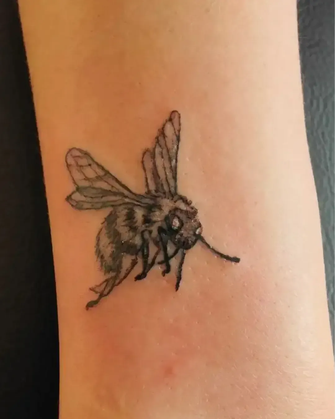Tatouage réaliste d’abeille en noir et gris – symbole de travail, énergie et connexion à la nature, réalisé par Magic Ink à Fribourg.