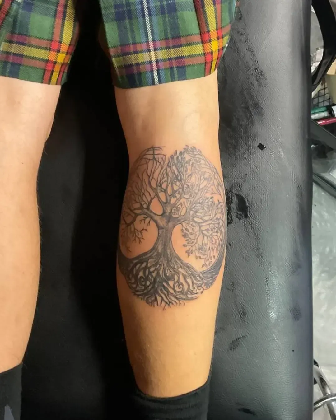 Tatouage de l’arbre de vie, encré avec élégance à l’arrière de la jambe. Ses branches s’élèvent vers le ciel tandis que ses racines s’enfoncent profondément, formant un cercle parfait qui symbolise l’équilibre, la connexion entre ciel et terre, et le cycle éternel de la vie. 🌳✨ Un design intemporel et spirituel, idéal pour ceux qui recherchent force, ancrage et harmonie intérieure. Réalisé par Magic Tattoo Ink à Fribourg.