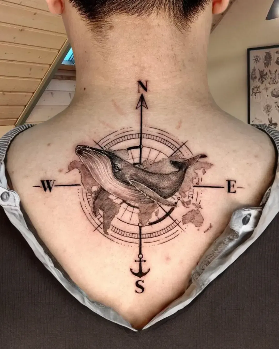 Tatouage artistique de baleine avec boussole et carte du monde – symbole de voyage, liberté et exploration, réalisé par Magic Ink à Fribourg.