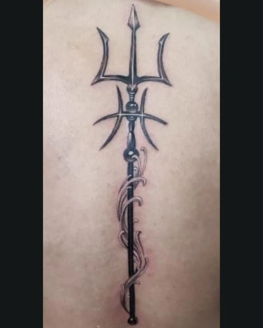 Tatouage de trident stylisé avec ornements et motifs tribaux – symbole de force, protection et pouvoir, réalisé par Magic Ink à Fribourg.