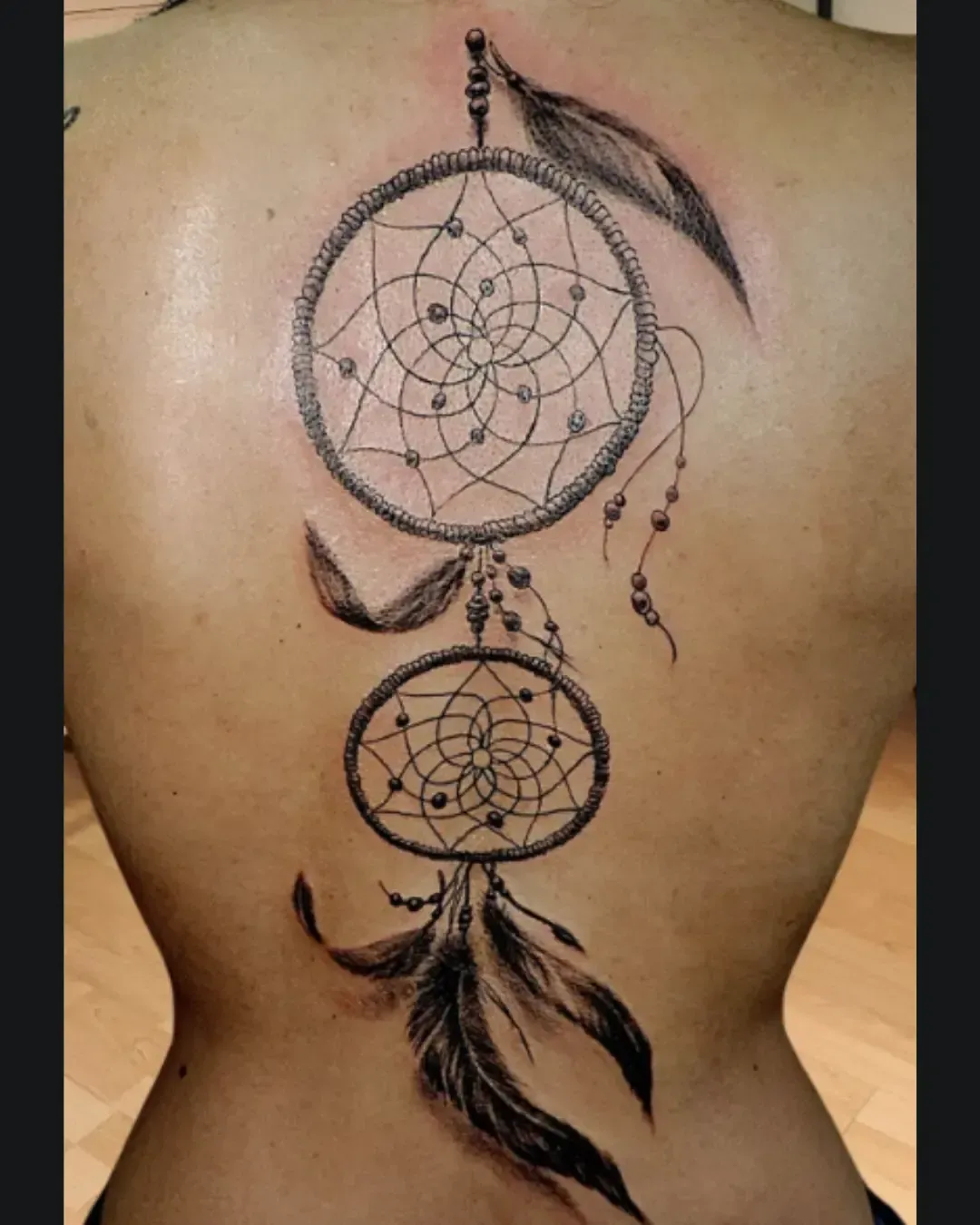 ChatGPT a dit :  Tatouage attrape-rêves réaliste avec plumes et perles – symbole de protection, spiritualité et connexion aux traditions amérindiennes, réalisé par Magic Ink à Fribourg.