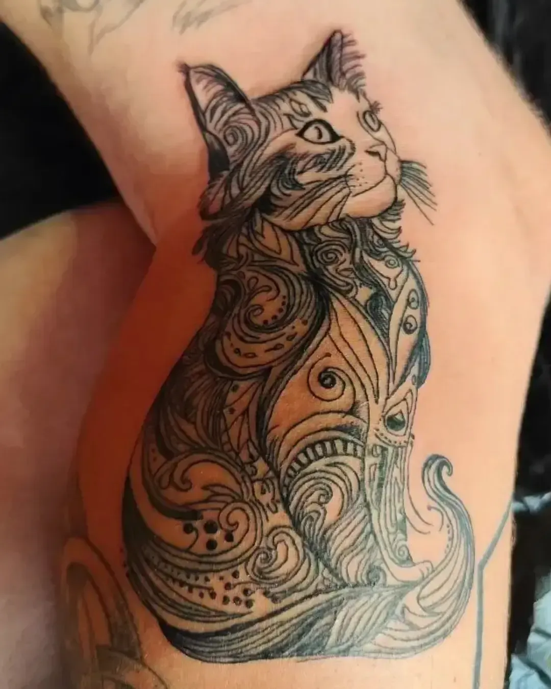 Tatouage artistique de chat ornemental avec motifs tribaux et lignes décoratives – symbole de mystère et élégance féline, réalisé par Magic Ink à Fribourg.