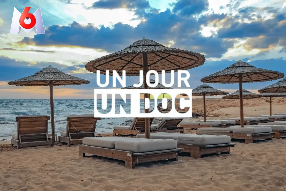 Premium-Strand bei Sonnenuntergang mit Holzliegen, exotischen Sonnenschirmen und Meerblick – Visual der Reportage „Un Jour Un Doc“ auf M6 über Urlaub und Reiseclubs
