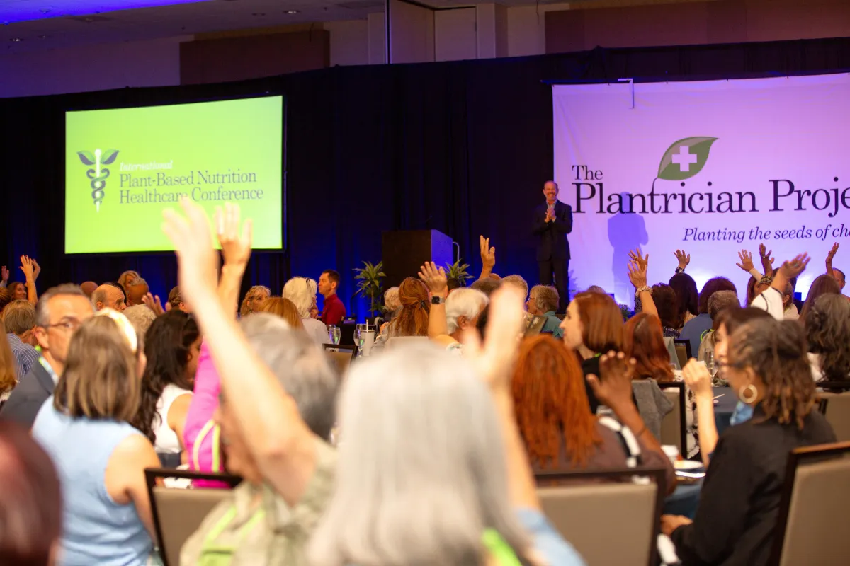 Scott Stoll MD speaking on stage at PBNHC 2025 with audience raising their hands