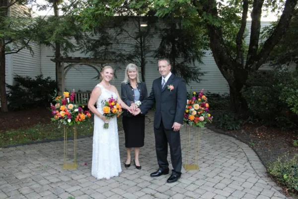 Wedding officiant celebrating with a newly married couple during an outdoor wedding ceremony.