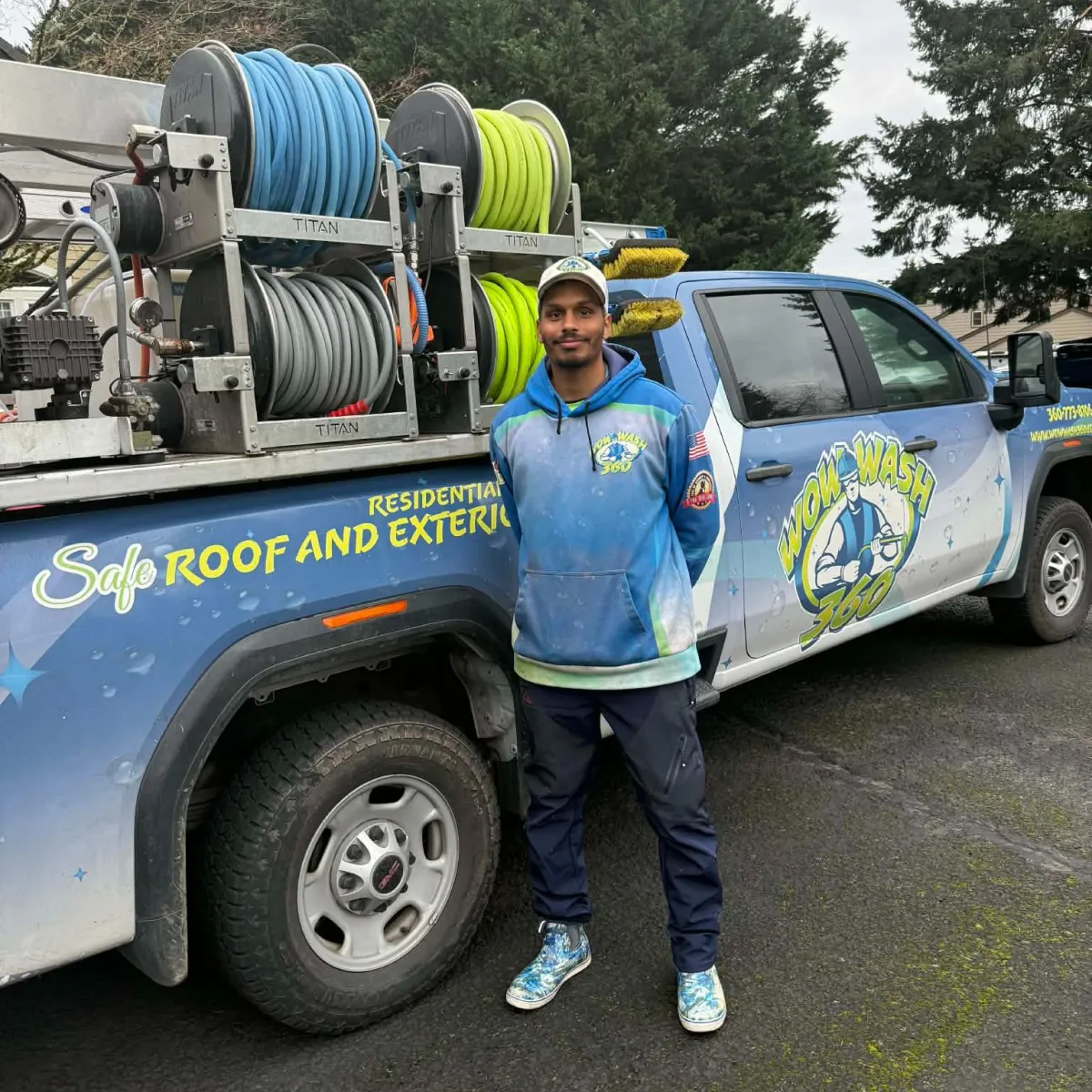 Employee at Wow Wash 360 smiling and giving a thumbs-up in front of cleaning supplies, showcasing the commitment to quality service in exterior cleaning.