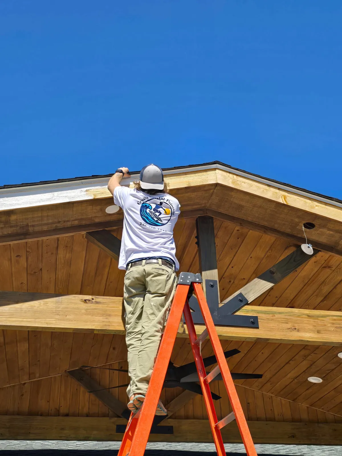 Painter finishing a porch ceiling on a Morehead City home