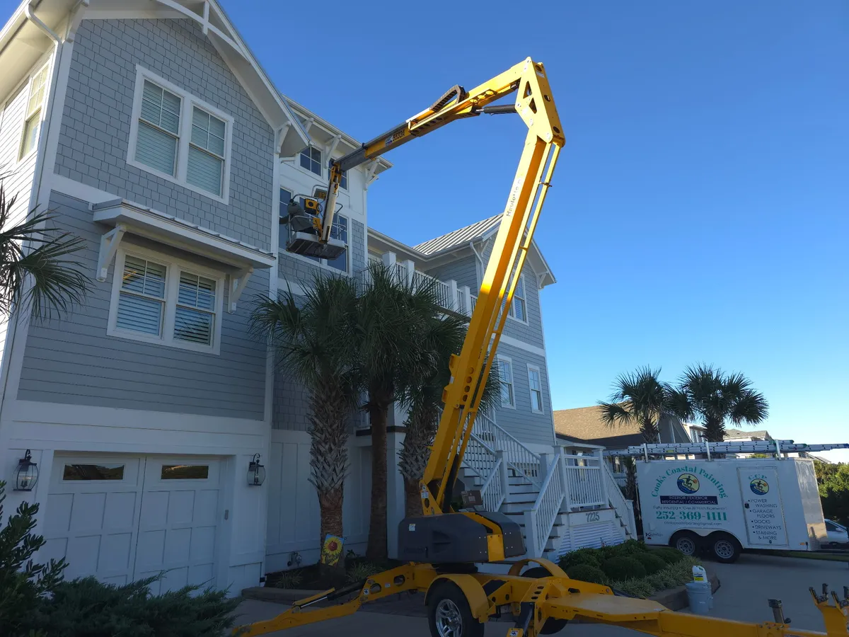 Lift positioned for exterior painting on a tall coastal home in Morehead City
