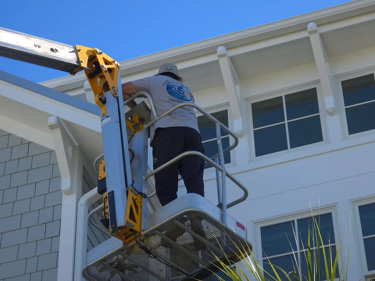 Painter on a ladder painting siding on a Morehead City home