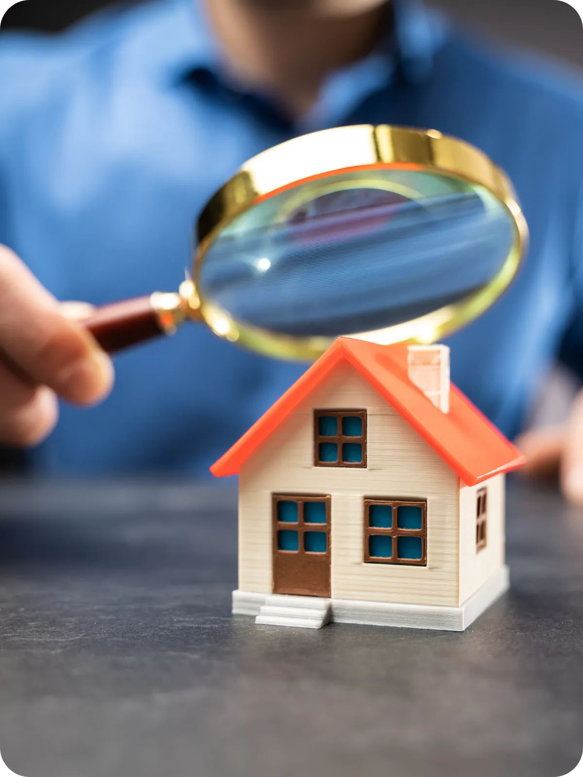 Close-up of a magnifying glass inspecting a miniature house, symbolizing detailed home inspections and professional certification services offered in Nashville and Middle Tennessee.