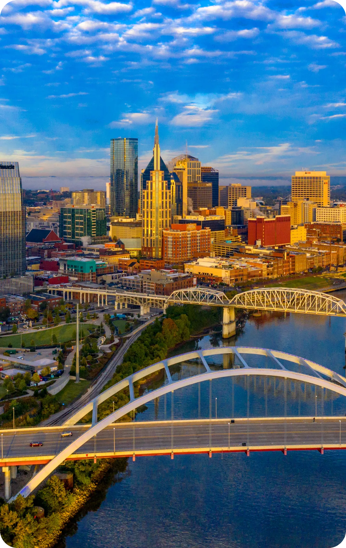 A vibrant aerial view of downtown Nashville, Tennessee, featuring the city skyline, bridges, and river at sunset, representing the primary service area for home inspection services.
