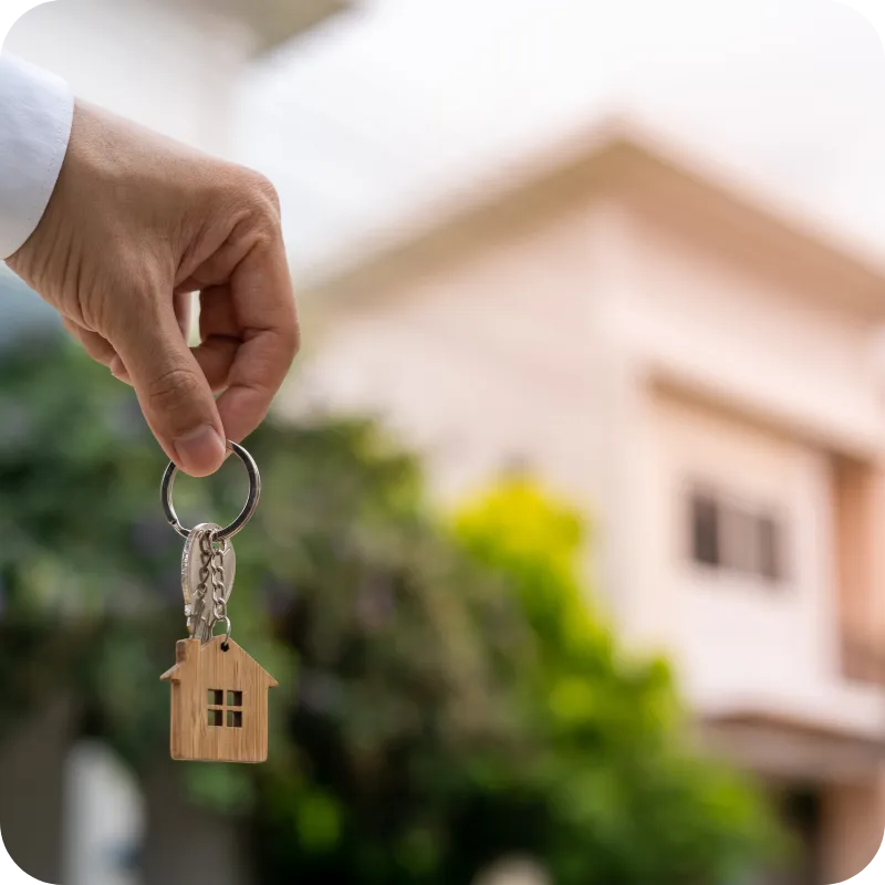 Hand holding a house-shaped keychain in front of a home, symbolizing the value of pre-listing home inspections for sellers in Nashville and Middle Tennessee.