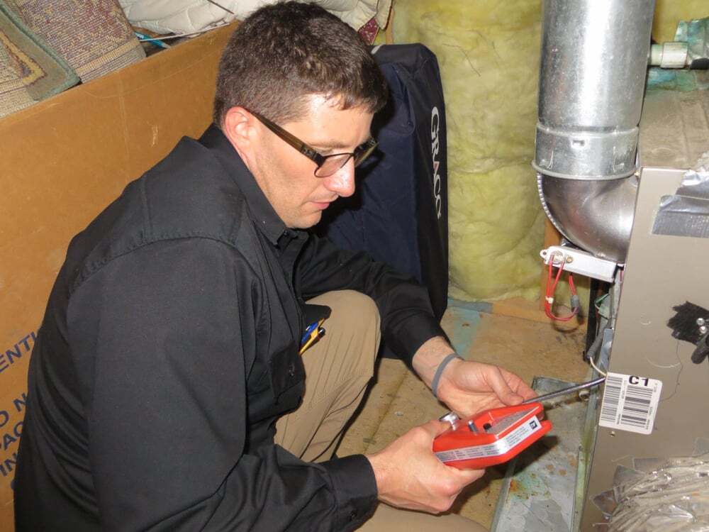 Home inspector evaluating a furnace and mechanical components during a professional re-inspection