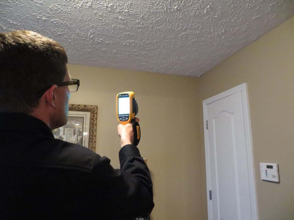 Home inspector using a thermal imaging camera to evaluate interior walls during a residential inspection