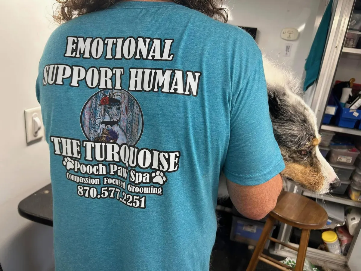Our staff wearing our Emotional Support Human shift while comforting a dog.