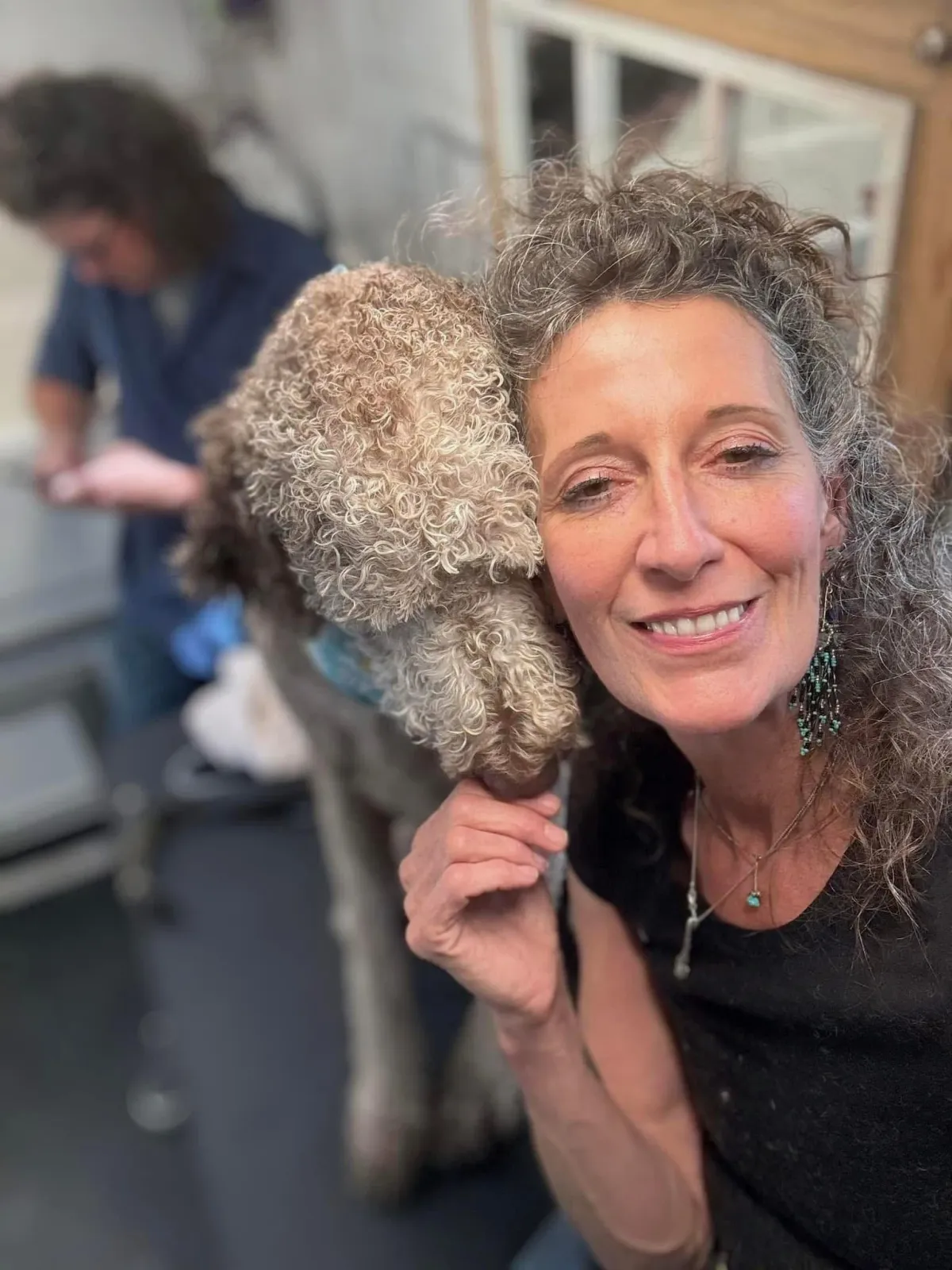Owner of The Tuquoise Pooch; Tracy Boyd smiling with a freshly groomed dog.
