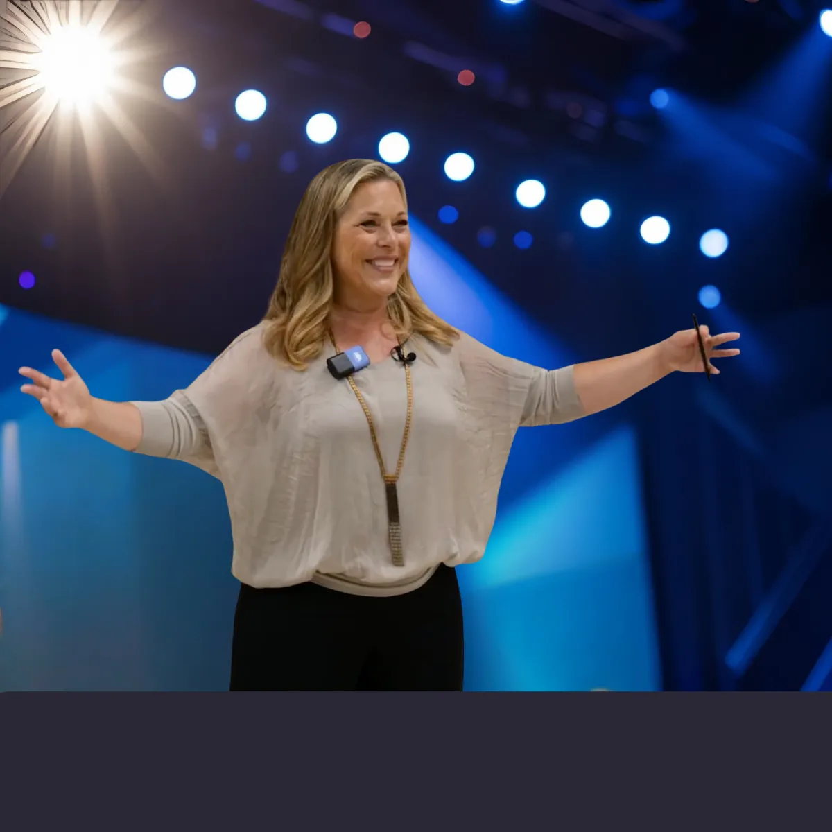 Pasha with arms wide open, speaking on Stage about Strengthening teams by prioritizing relationships, respect, and inclusion.