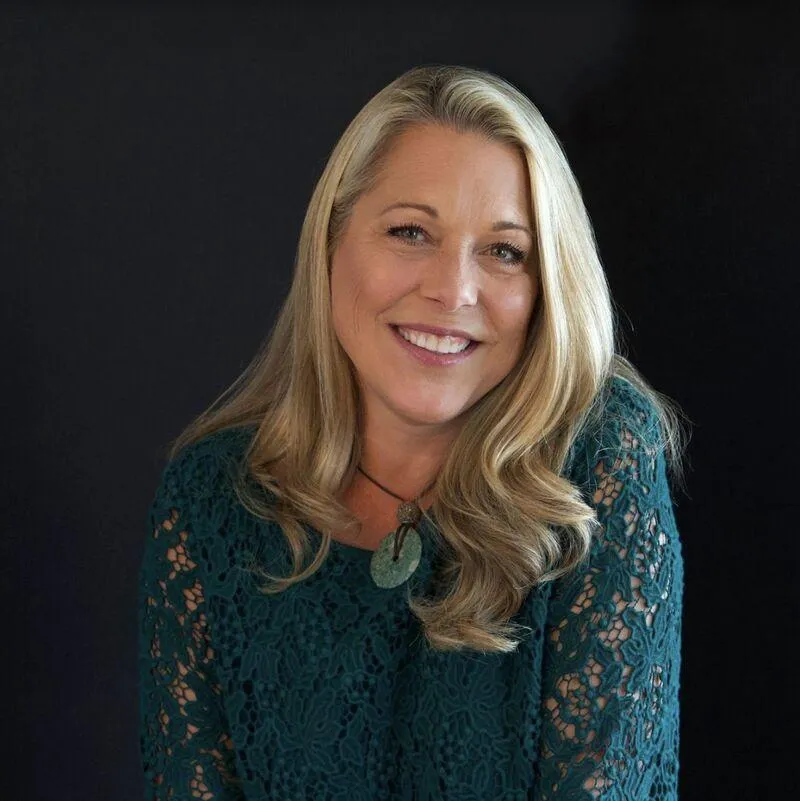 Pasha with exuberant smile on stage with microphone in one hand, and other arm is lifted in the air engaged with audience.