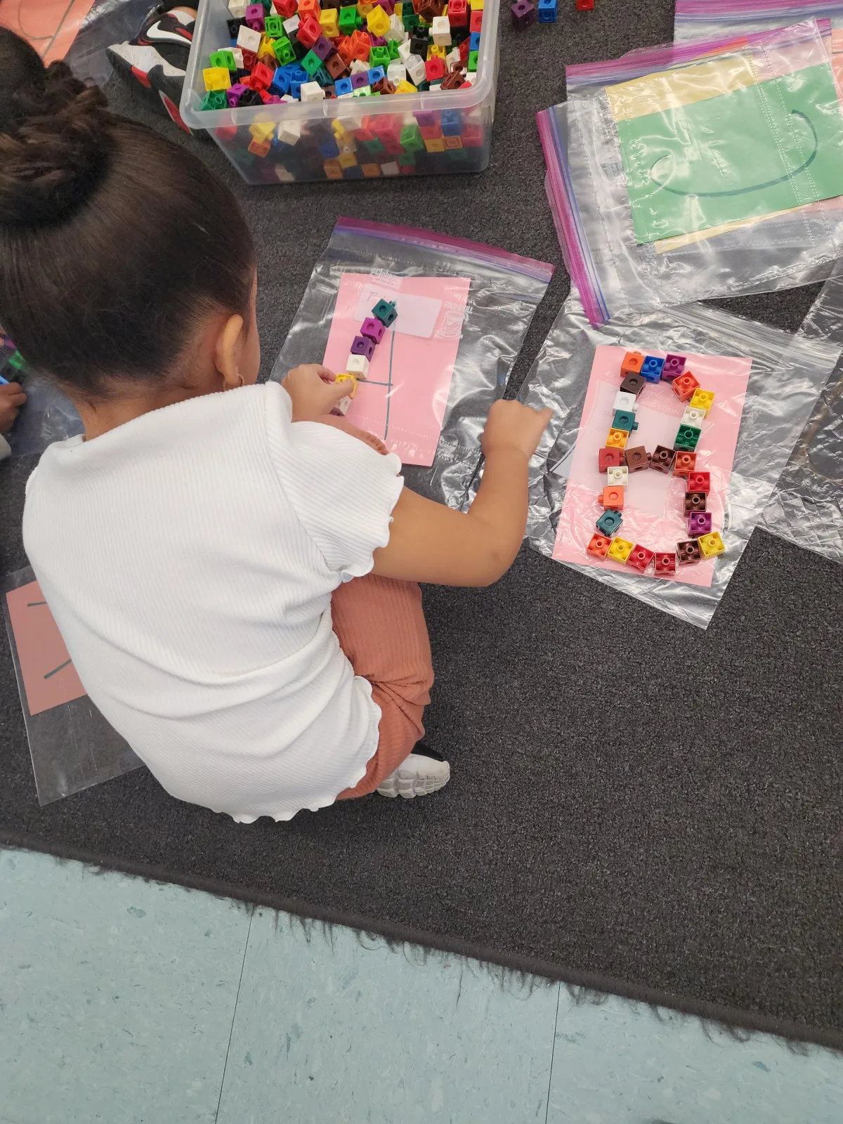 Child writes A in green sand