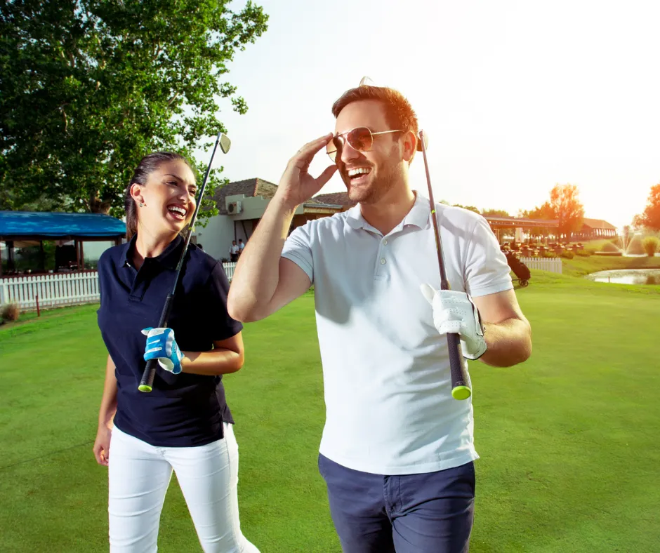 A smiling couple walking with golf clubs on a golf course