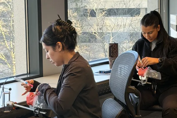 Two dental assistant students practicing hands-on clinical skills on dental training models during a course at Dental AssistEd in Chicago, Illinois