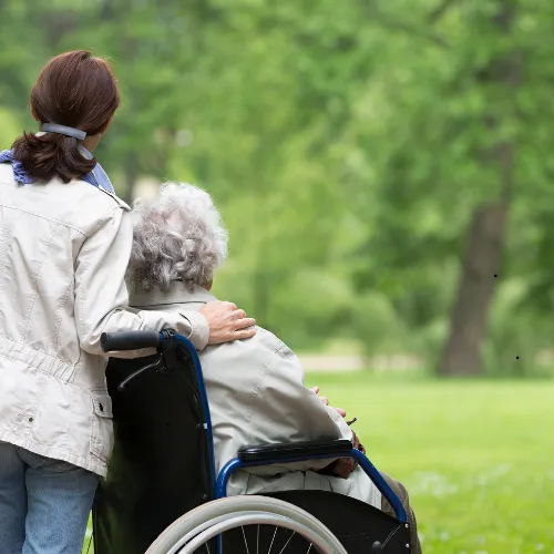 A picture of an elderly lady in a wheelhair being care for at an assisted living center