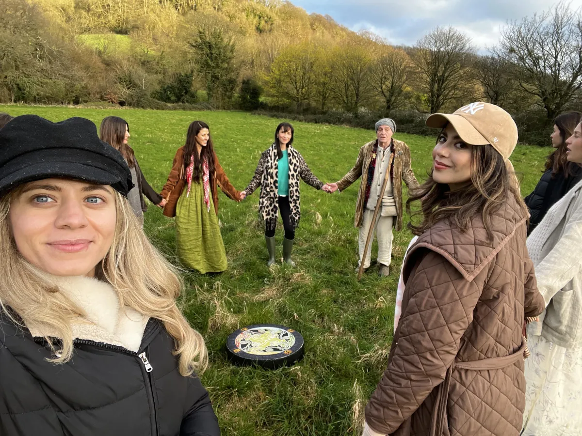 Sabrina Stocker chanting in a sister circle, joined by women holding hands in a sacred cacao ceremony focused on connection and healing.