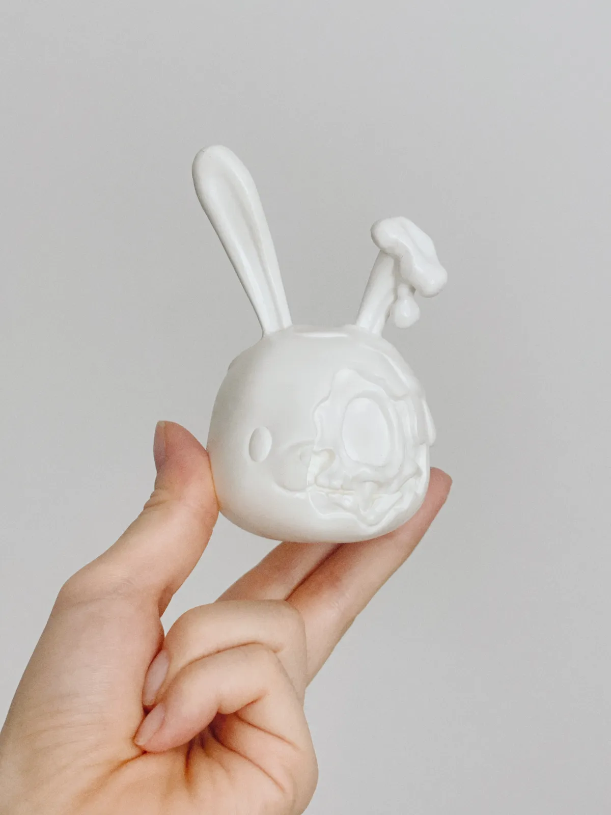 An unpainted white Goodbunny skull blank held in a hand