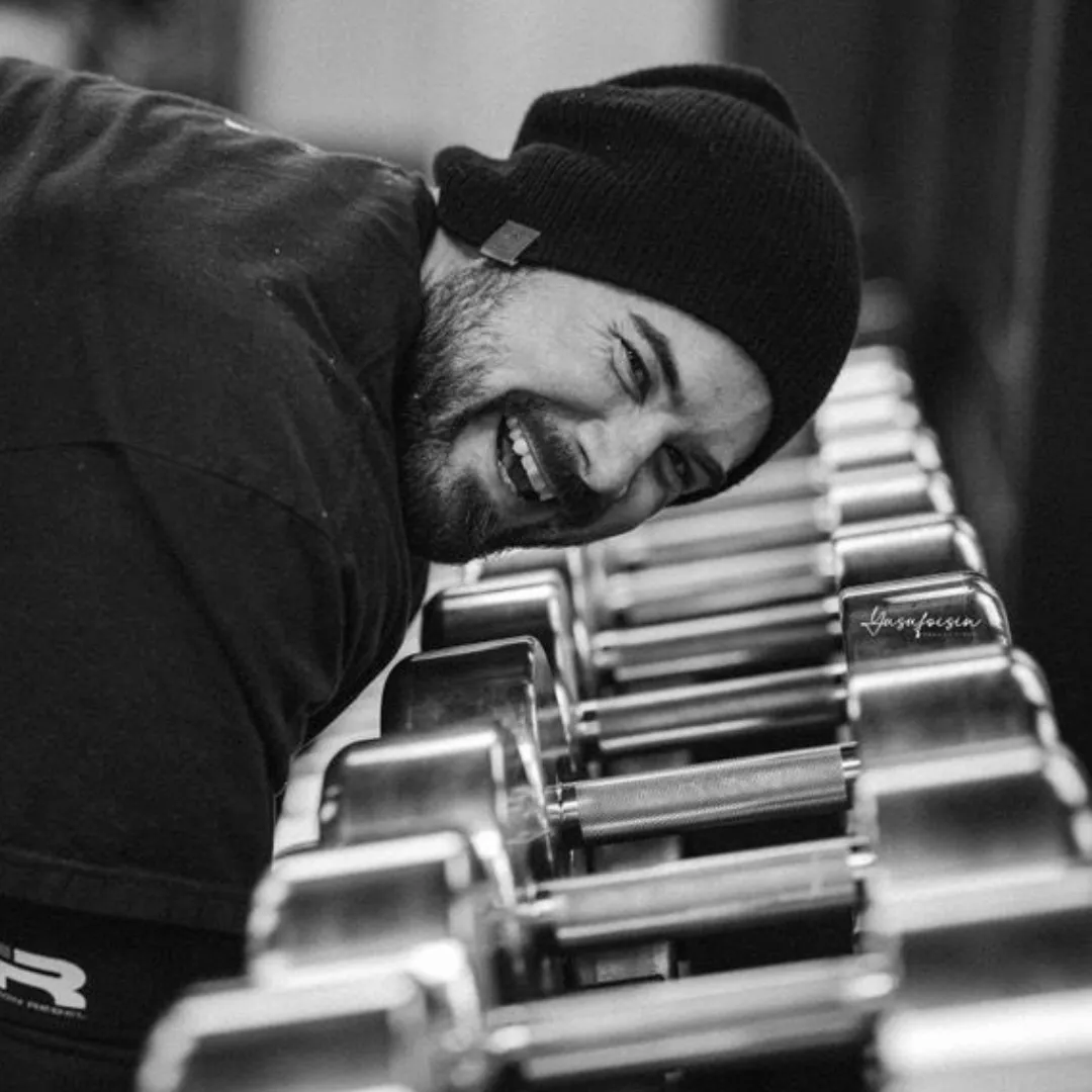 topless man in black pants holding black and yellow exercise equipment