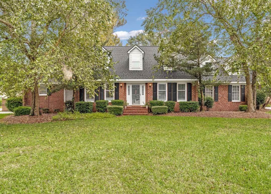 A purple, abstract sculpture stands against green.