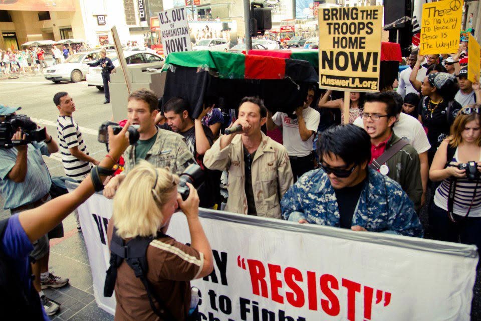 Kelvin Rodeo, the author, is seen marching alongside fellow anti-war veteran activist Mike Prysner, while holding up a sign during a march on the streets of Hollywood on the 11th anniversary of the War in Afghanistan in 2012.