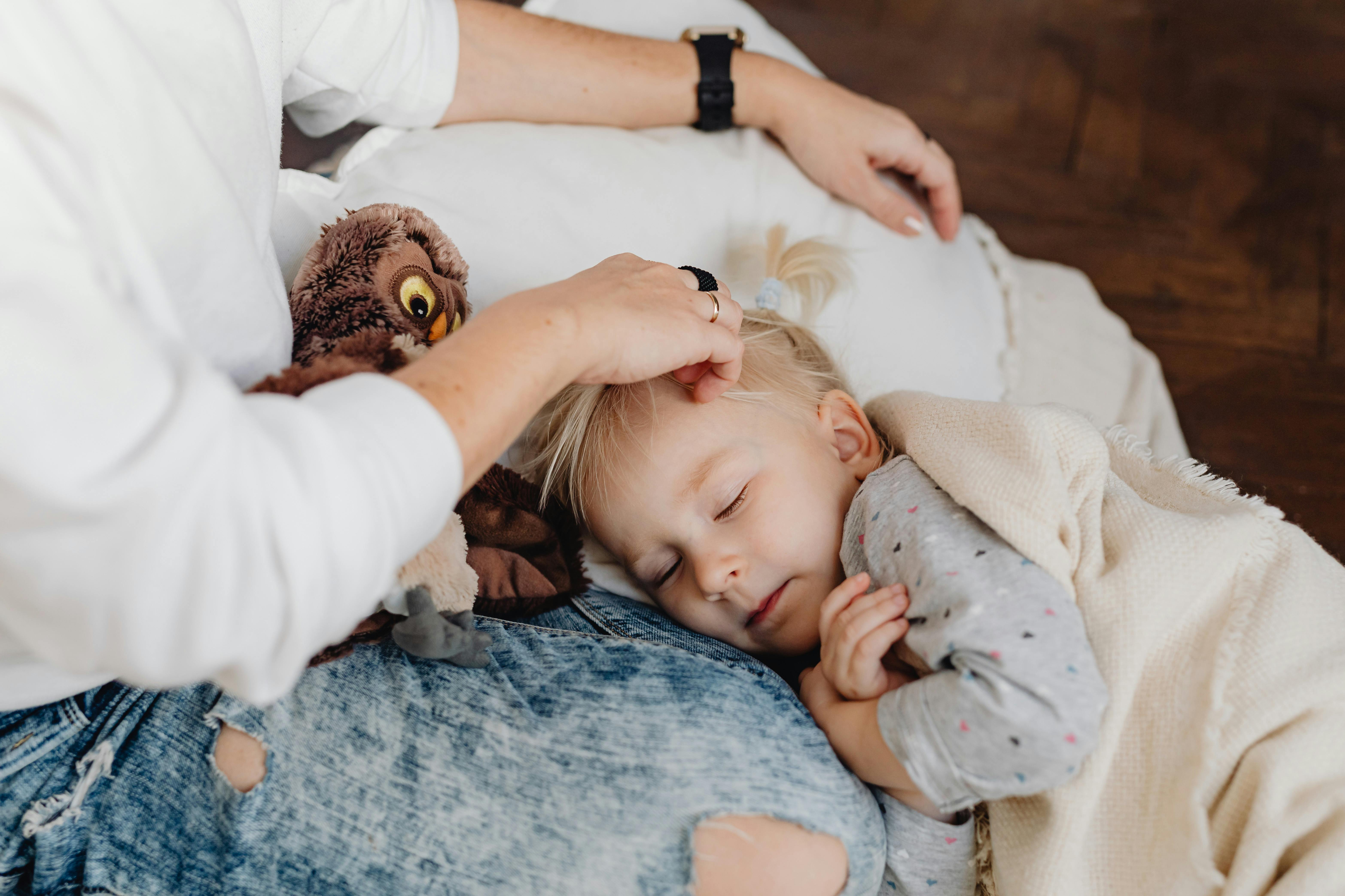 Parent gently settling a child to sleep in bed during a calm bedtime routine