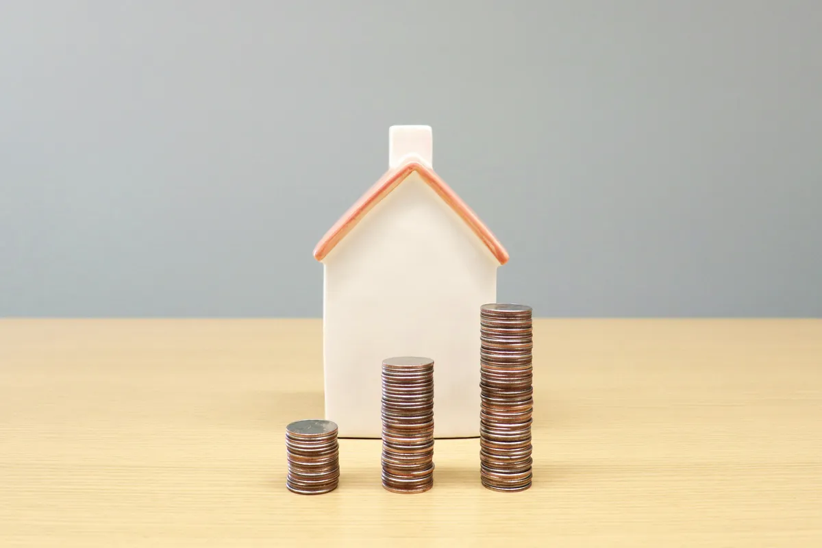 Model house next to stacks of coins - Colorado property taxes and selling a Littleton home, Simon Dzienis