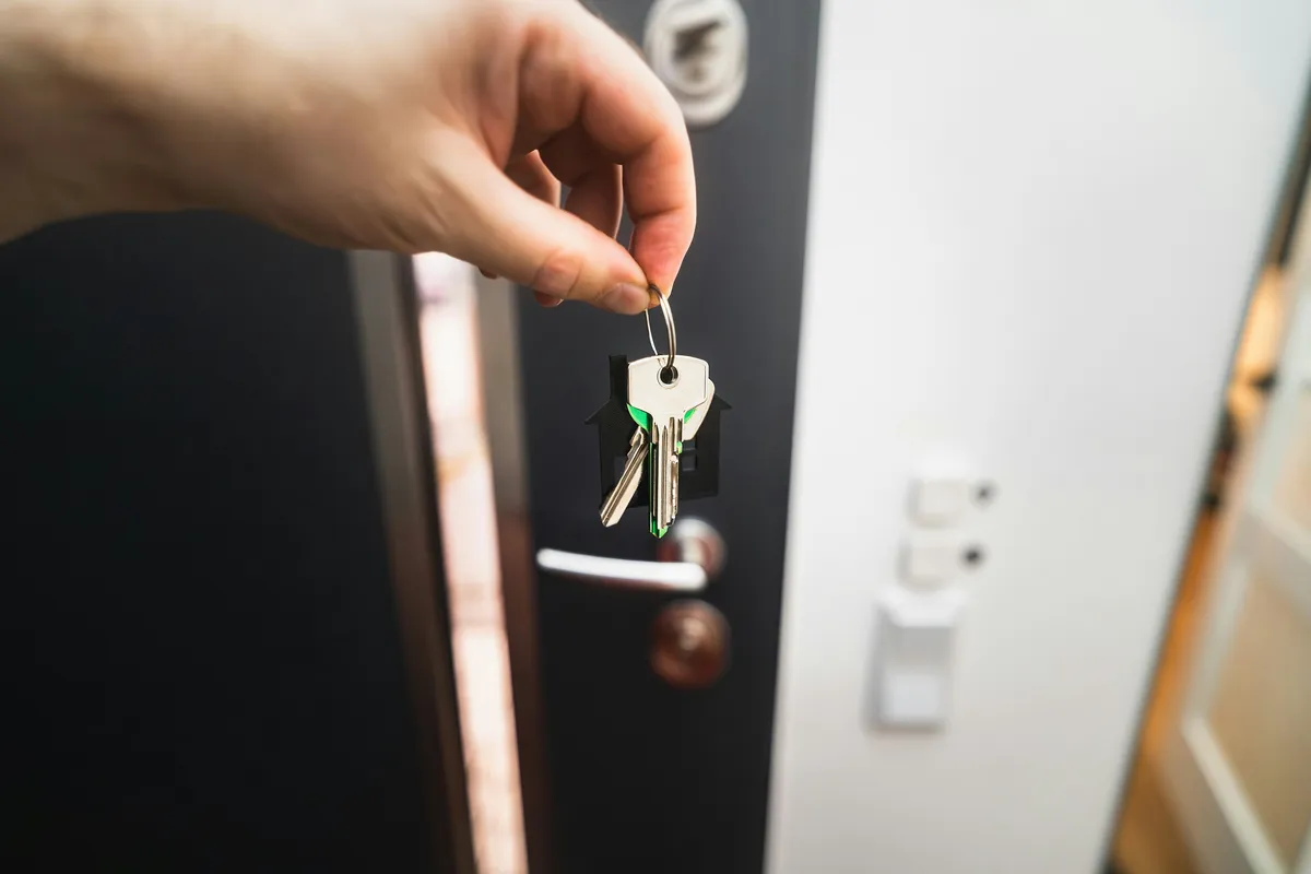 Hand holding house keys at a front door - lockbox vs agent-present showings in Littleton, Simon Dzienis