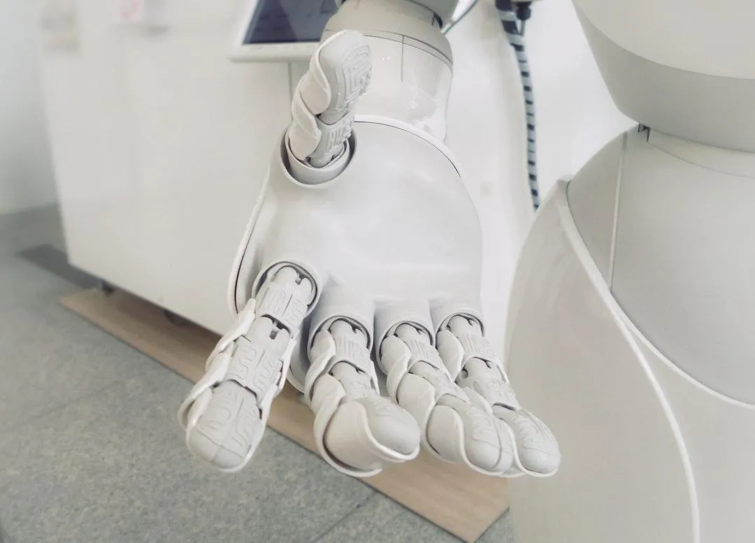 Close-up of a white robotic hand reaching out, representing AI that reduces busywork and delivers proven results.