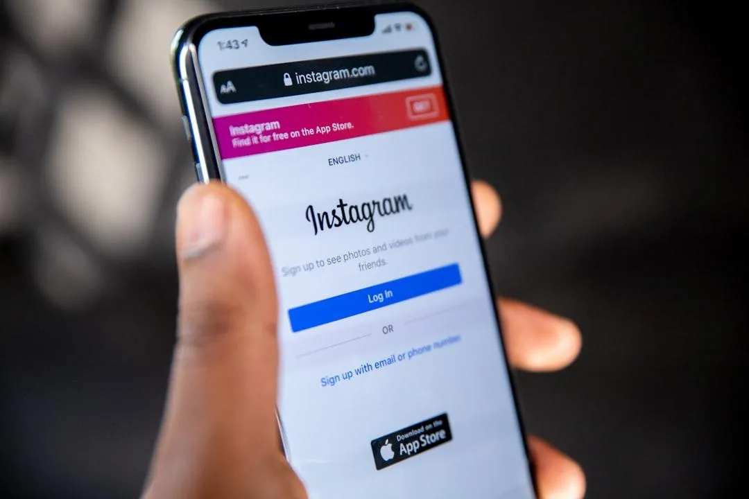 Hand holding a smartphone displaying the Instagram login page, representing mobile access to social networking and content sharing.