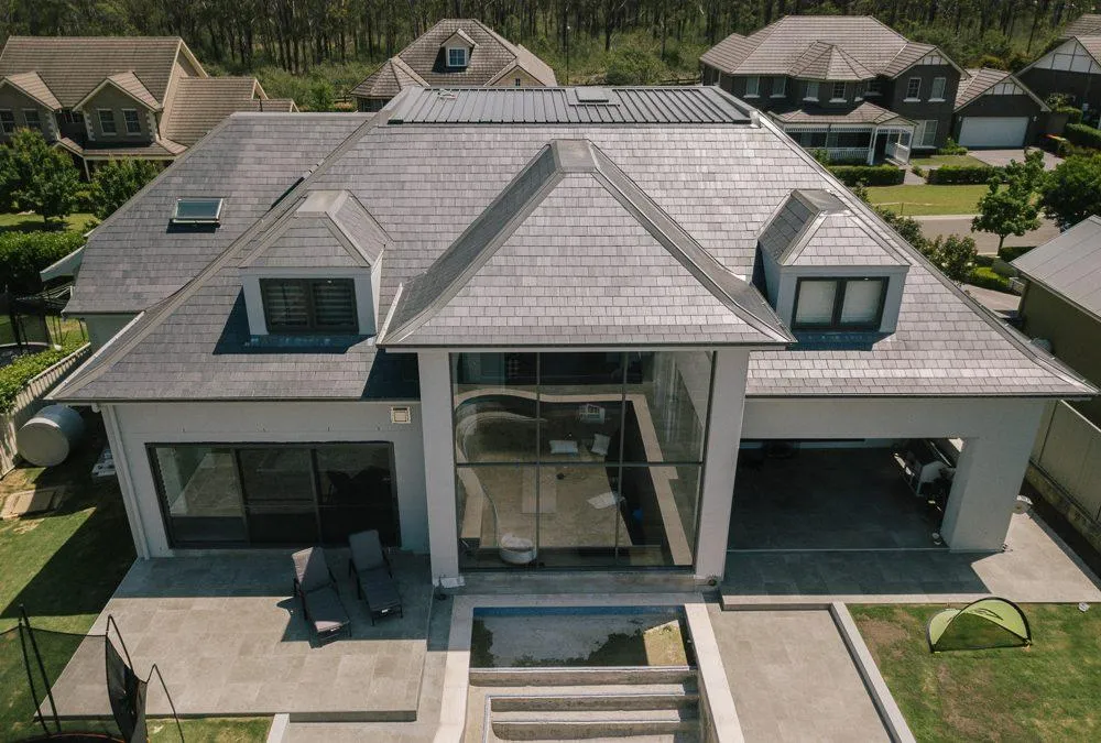 Overhead perspective of a house featuring a large roof, highlighting its structure amidst the surrounding landscape