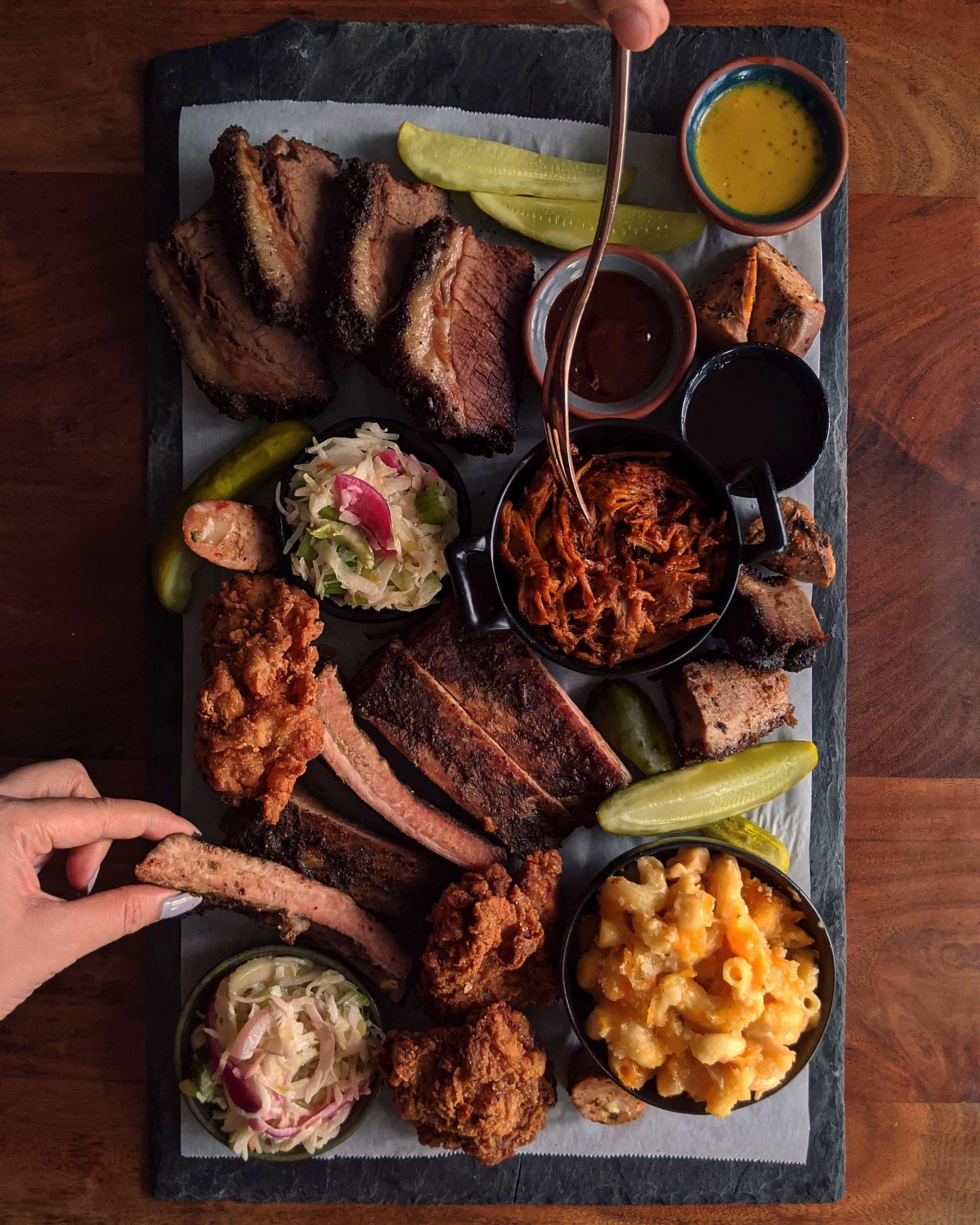 The Carbon Bar Pit Master Platter and cocktails on a dark wooden table