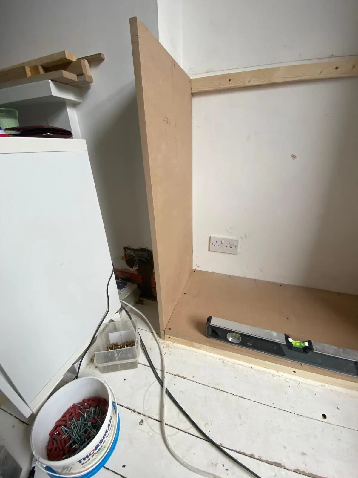 Internal view of custom carpentry showing the sturdy frame construction for built-in alcove cupboards around existing electrical sockets.