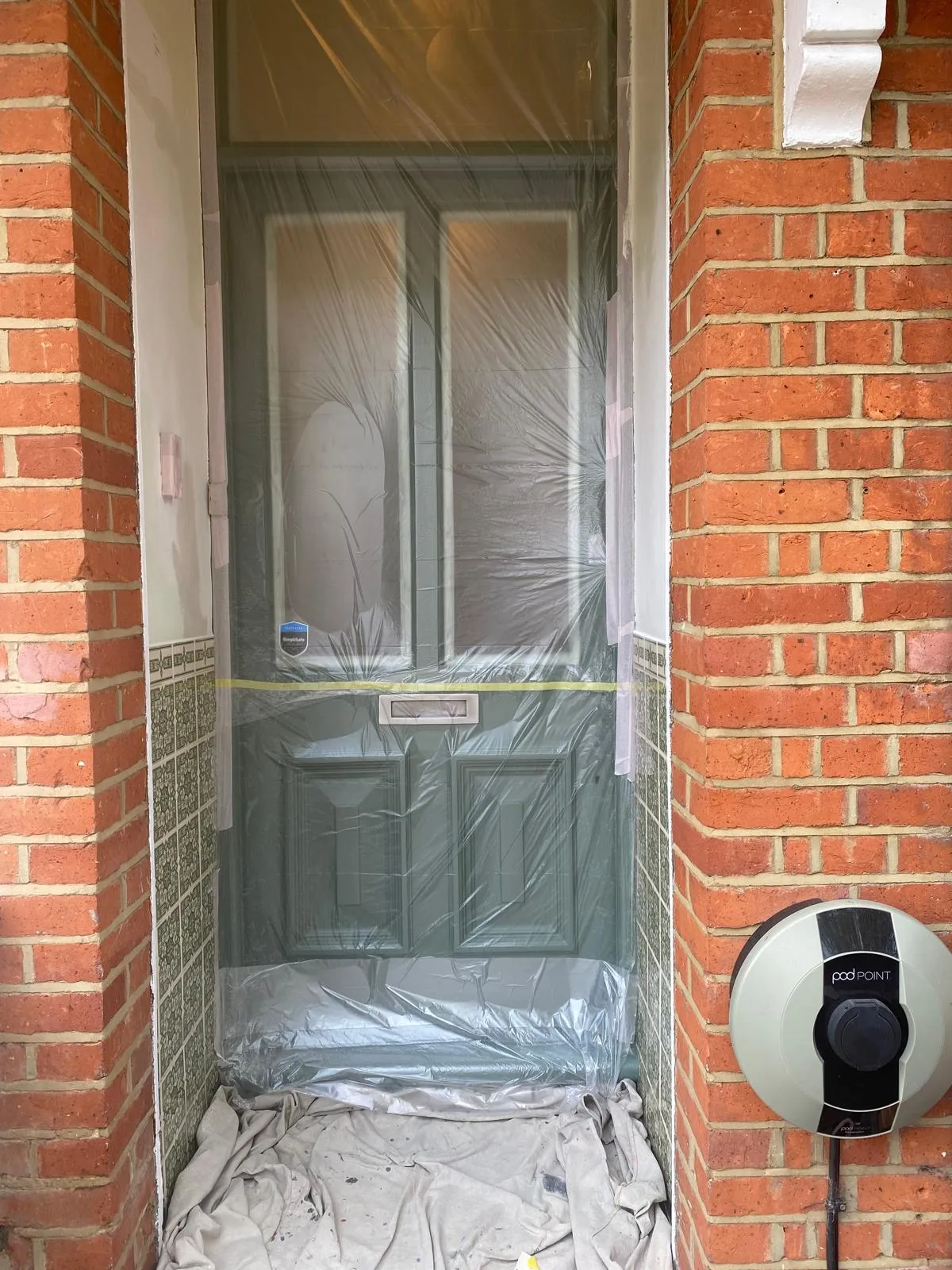 Professional masking of a Victorian door with protective sheeting in Epsom, during a durable exterior wood restoration and painting project.