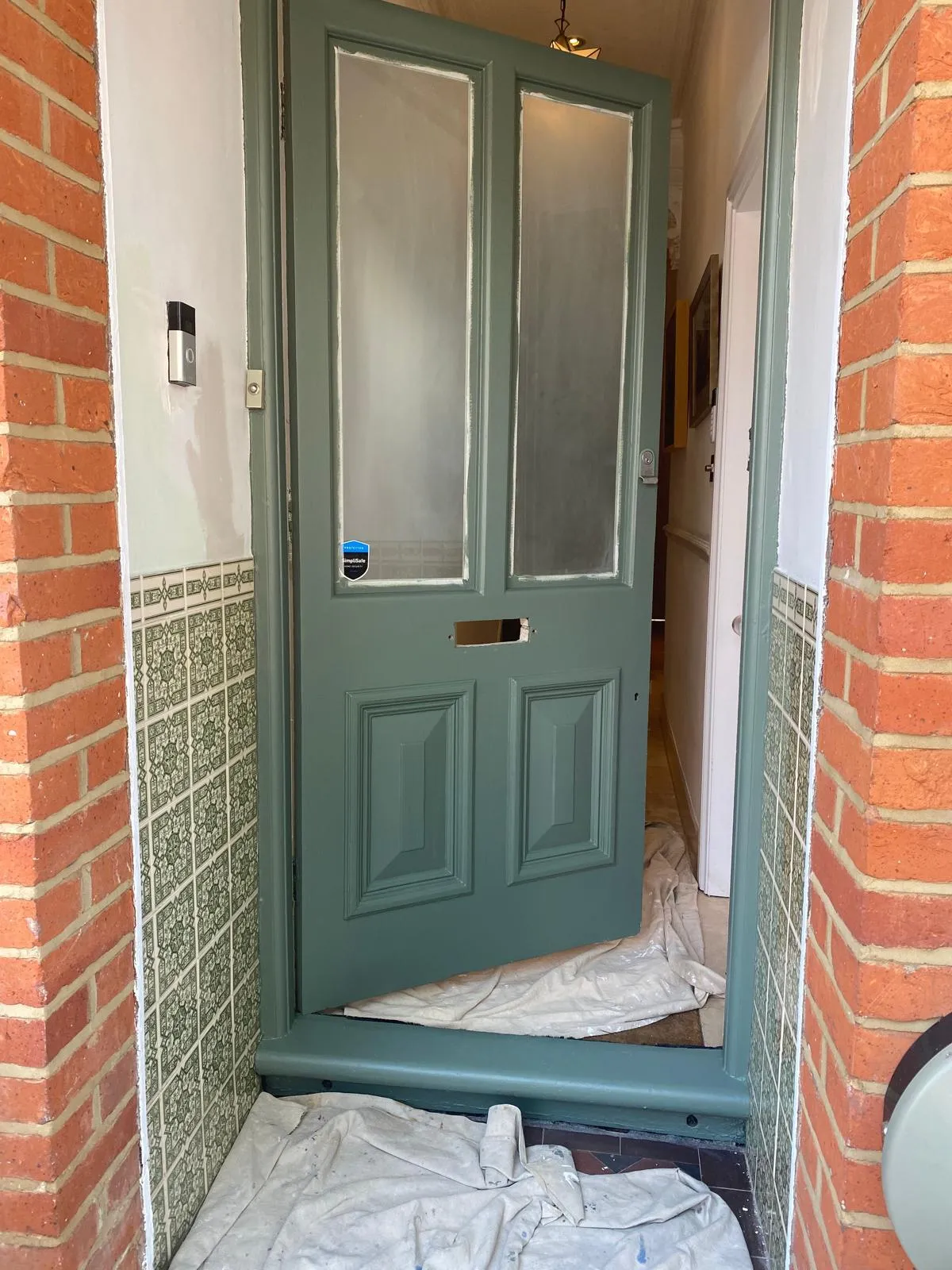 Detail shot of precision masking around a Victorian door letterbox and panels, ensuring clean paint lines for a professional door restoration in Surrey.