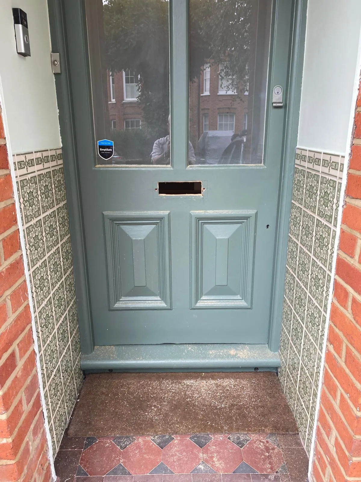 Close-up of a restored timber front door in Epsom, showing a sharp green satin finish after professional wood grain repair and priming.