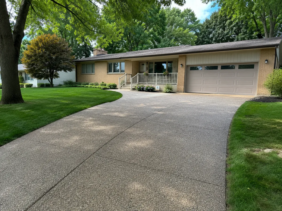 Exposed-aggregate concrete driveway at a brick ranch home in Racine, WI by GM Concrete