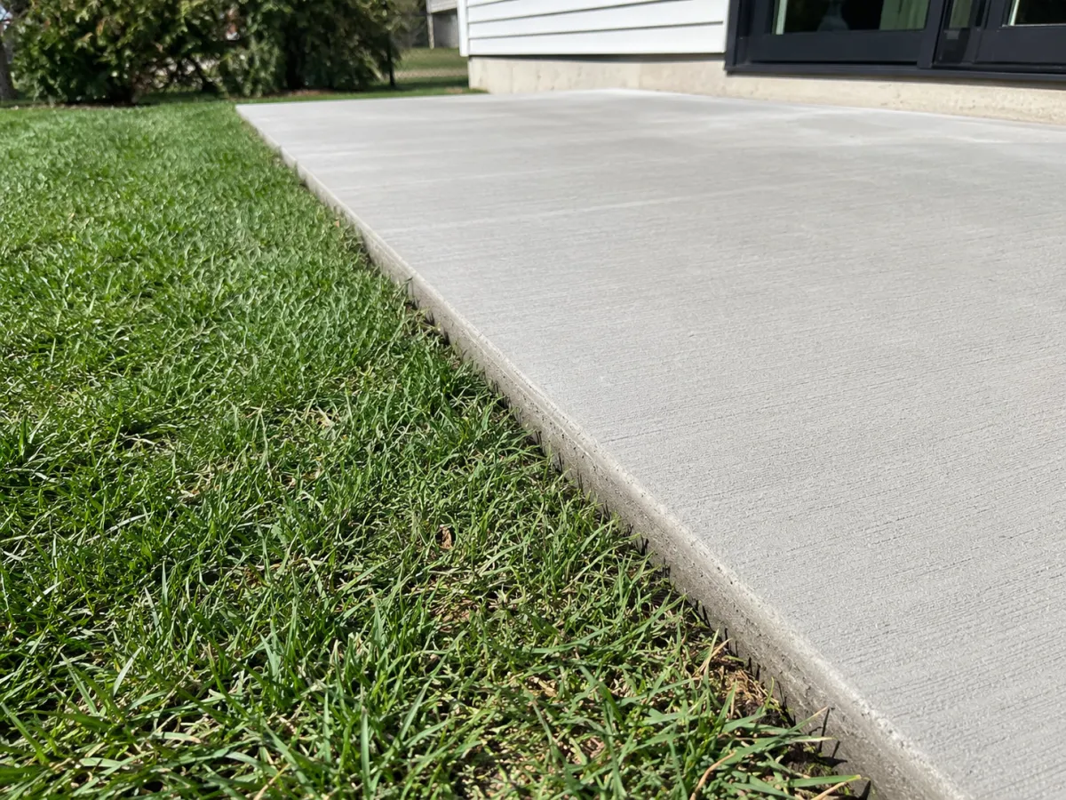 Wide finished concrete driveway along a green lawn in Racine, WI by GM Concrete