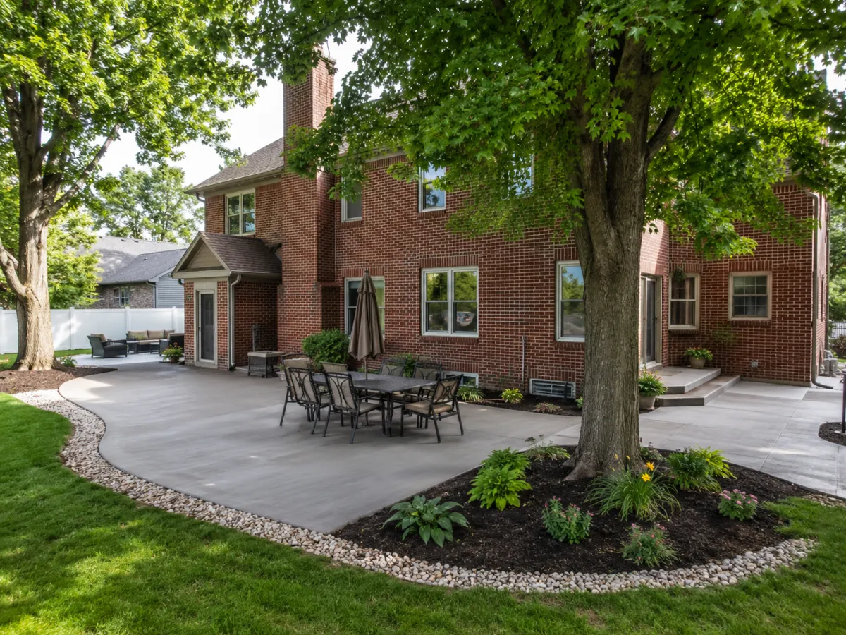 Concrete patio wrapping a tree at a brick home in Racine, WI by GM Concrete