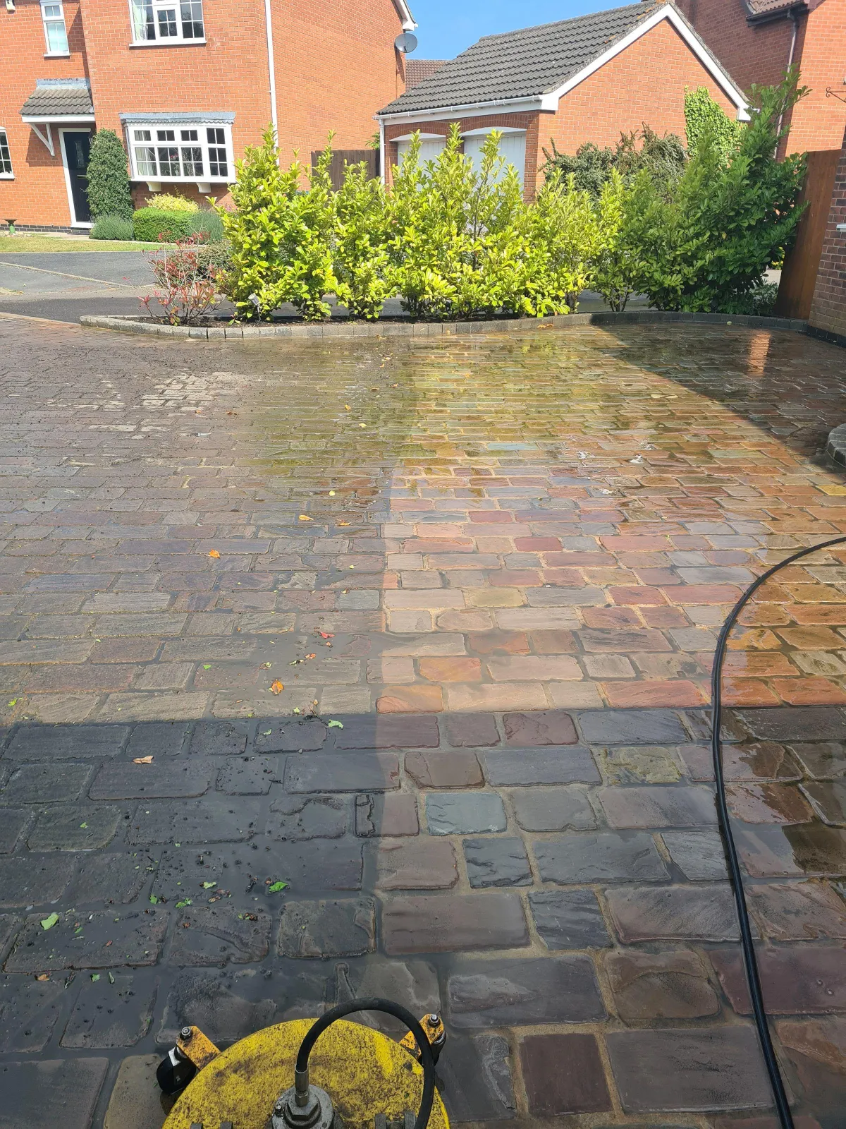 Before and after driveway pressure washing showing a clean section next to dirty paving