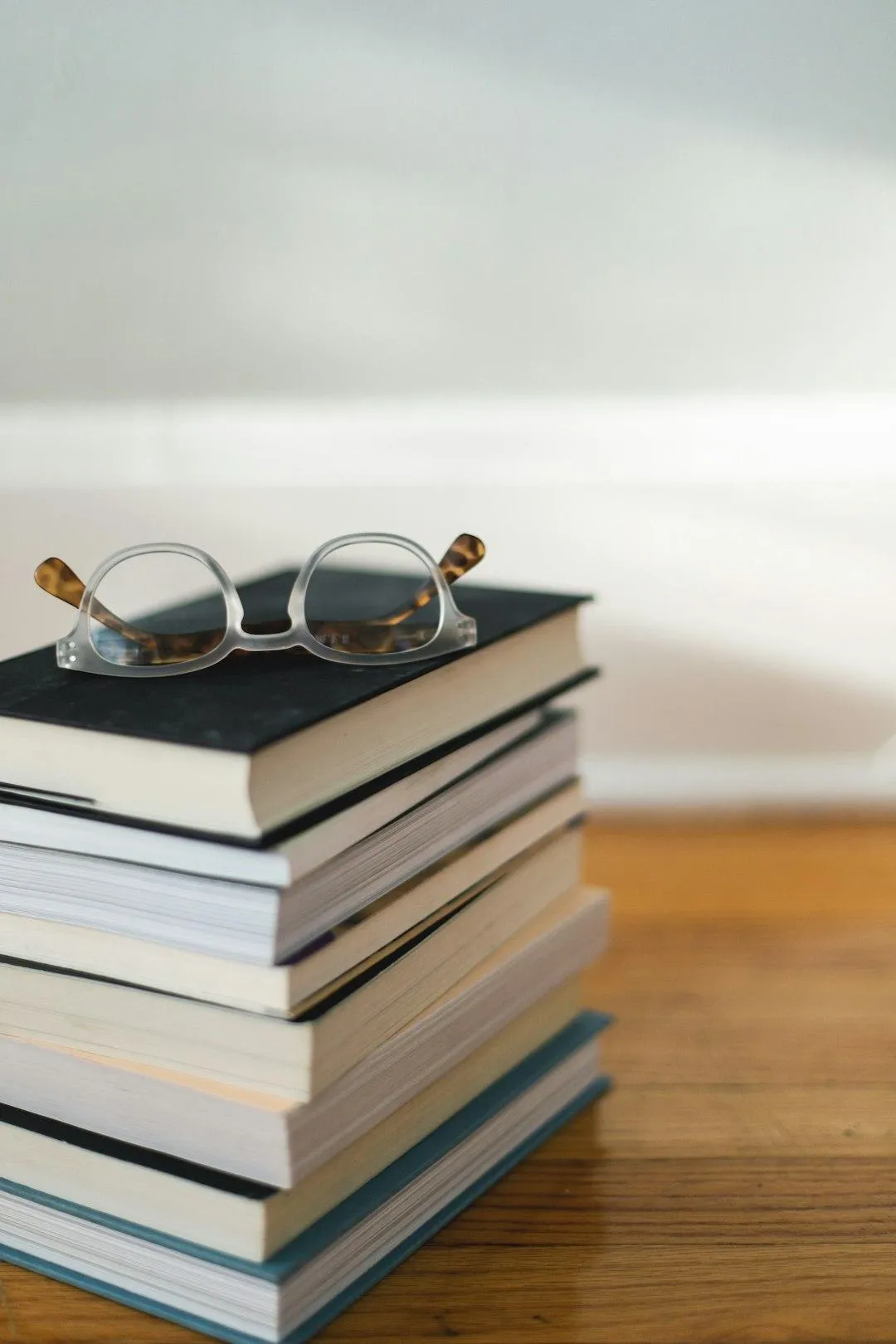 A stack of books and glasses representing Dr. Emily Altunay's studies to become a psychologist