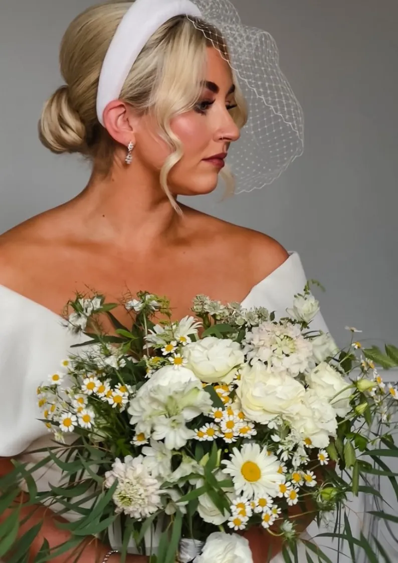 Beautiful blonde bride with large floral arrangement and warm glowy make up